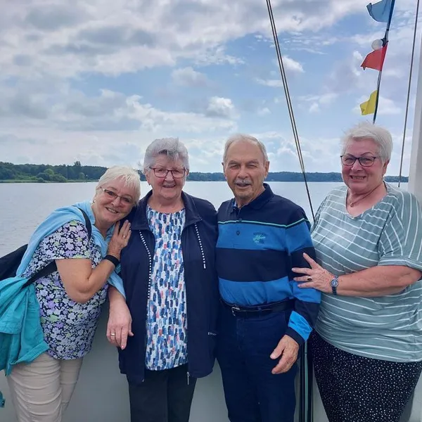 Vier Menschen stehen an der Reling von einem Boot und schauen in die Kamera