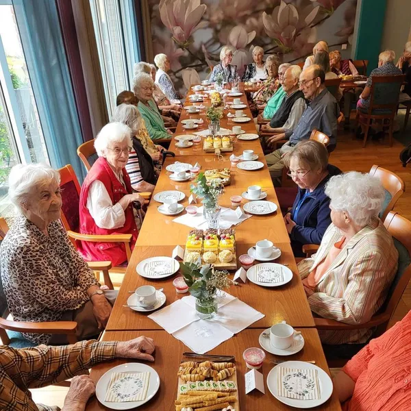 Menschen sitzen an einer gedeckten Tafel