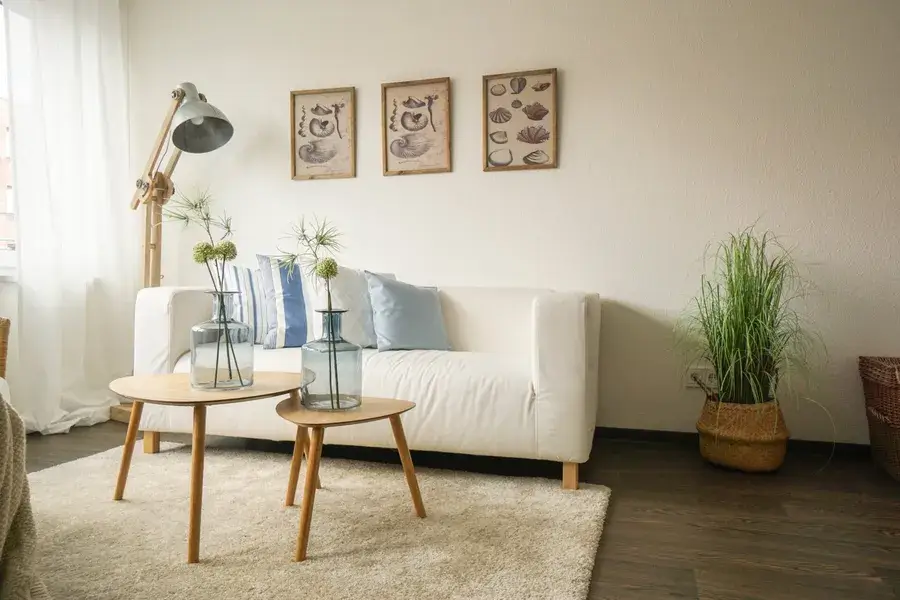 weißes Sofa, davor zwei Tische mit Blumenvasen auf einem Teppich
