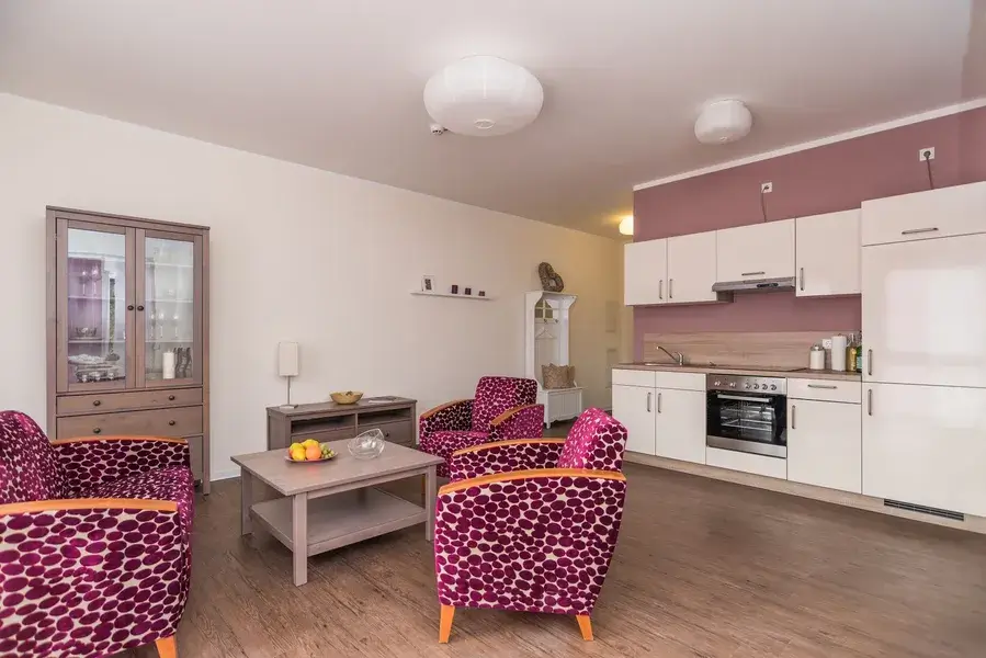 offene Wohnküche mit bunten pinken Sesseln im Vordergrund