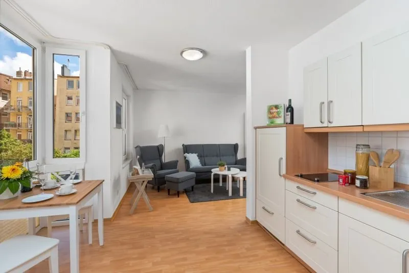 rechts Küchenezeile, links Essbereich, im Hintergrund Sessel und Sofa