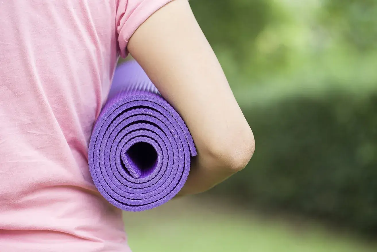 Nahaufnahme einer Yogamatte, die unter einem Arm eingeklemmt ist