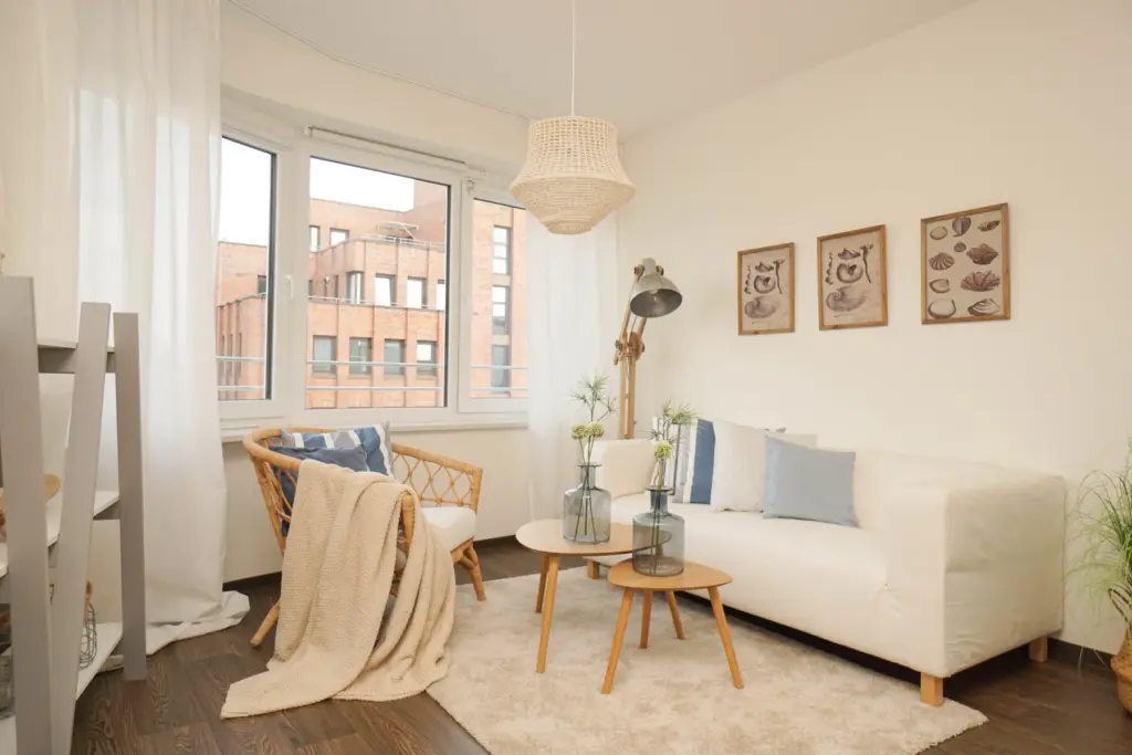 Sitzecke mit Sofa uns Sessel in hellen Farben vor einem großen Fenster