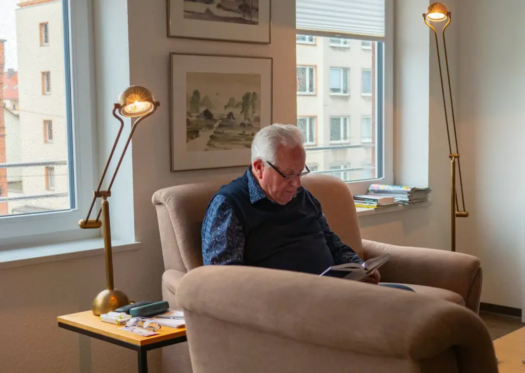 alter Mann sitzt in einem Sessel und liest ein Buch