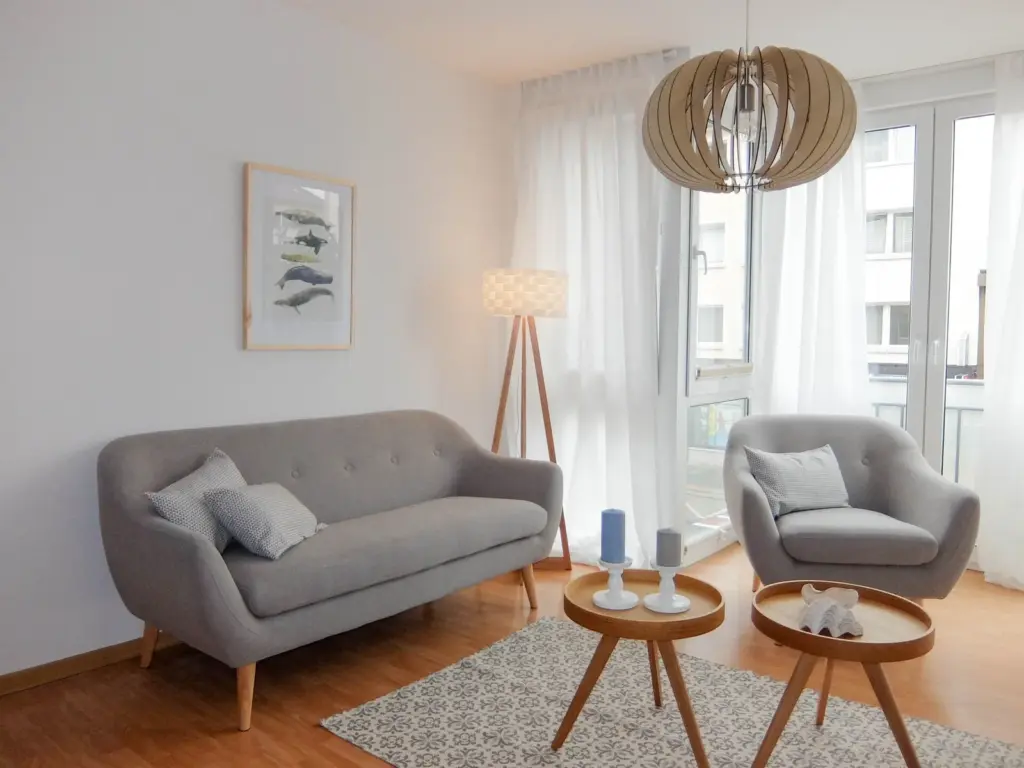 Sofa mit Sessel stehen um zwei Beistelltische mit Deko