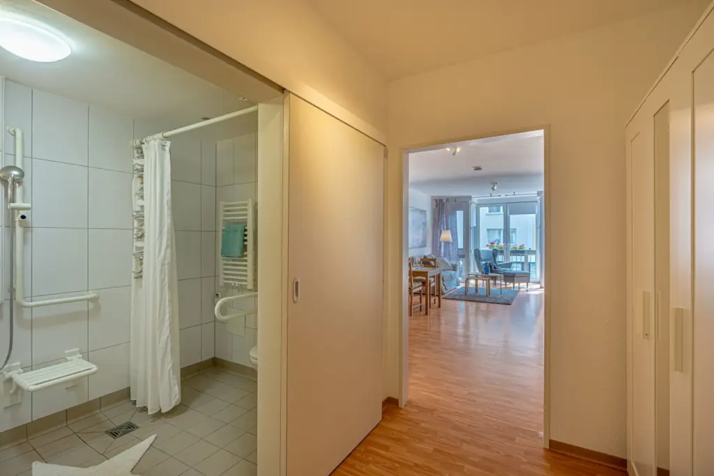 Rechts ein barrierefreies Badezimmer, im Hintergrund Blick in den Wohnbereich