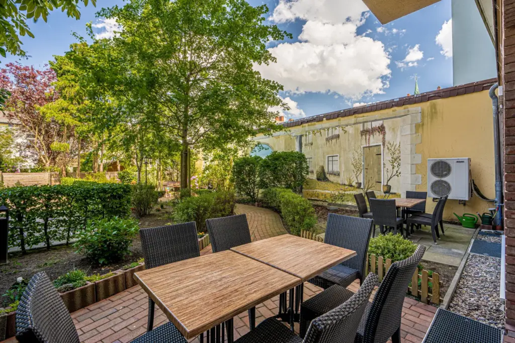 Terrasse einer Wohnanlage umgeben von vielen Bäumen und hecken